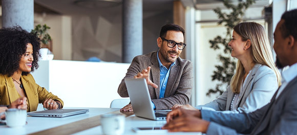Business professionals collaborating around a table in a bright modern office, focused discussion, light walls